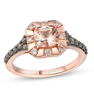 A rose gold ring featuring a cushion-cut center stone, surrounded by smaller round diamonds, with additional dark stones set along the band.