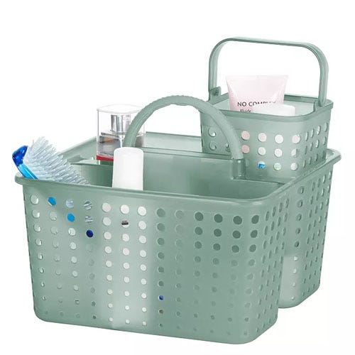 Two green plastic storage caddies with perforations, featuring handles and containing various bath and grooming items like a toothbrush, a tube, and a bottle.