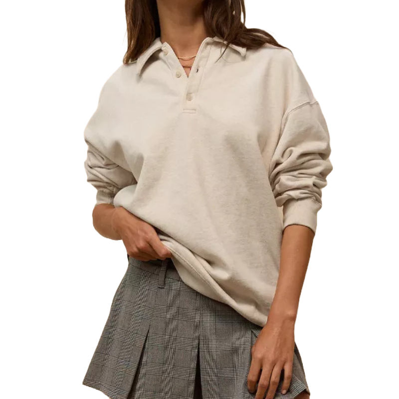 A relaxed-fit, cream-colored fleece polo sweatshirt with a collared neckline and buttons, paired with a gray plaid pleated skirt.