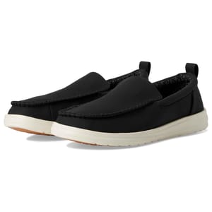 Hey Dude Men's Loafers feature a black upper with moccasin-style stitching, white soles for casual appeal, and pull tabs for easy wear. They have a comfortable, laid-back design suitable for everyday use.