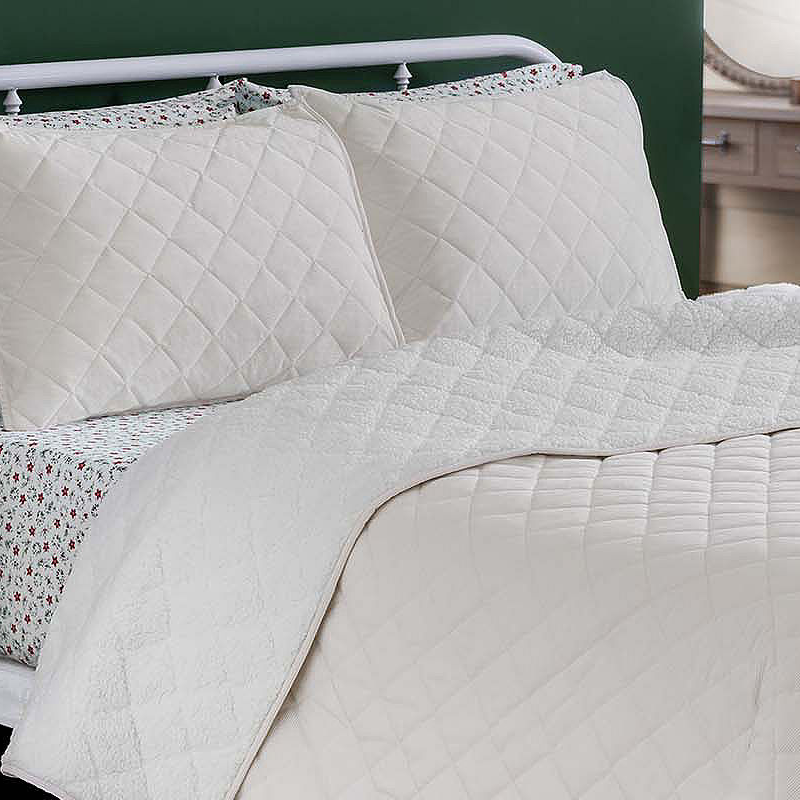 Martha Stewart Queen Sherpa Quilt Set features a quilted white design with matching pillow shams and patterned sheets underneath, creating a cozy and elegant look.