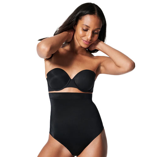 A woman is wearing a black strapless bra and high-waisted shapewear.