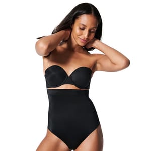 A woman is wearing a black strapless bra and high-waisted shapewear.