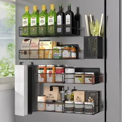 Wall-mounted metal racks hold bottles of olive oil, packaged snacks, canned goods, and jars. A utensil holder contains kitchen tools, and there is a paper towel dispenser on the side. The setup maximizes kitchen storage efficiently.