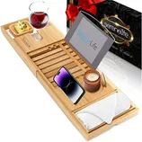 Bamboo bath caddy tray featuring a slot for a wine glass, a soap holder, a stand for a tablet, space for a phone, candle, and towel. Packaging in the background.