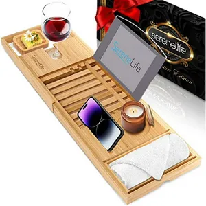 Bamboo bath caddy tray featuring a slot for a wine glass, a soap holder, a stand for a tablet, space for a phone, candle, and towel. Packaging in the background.