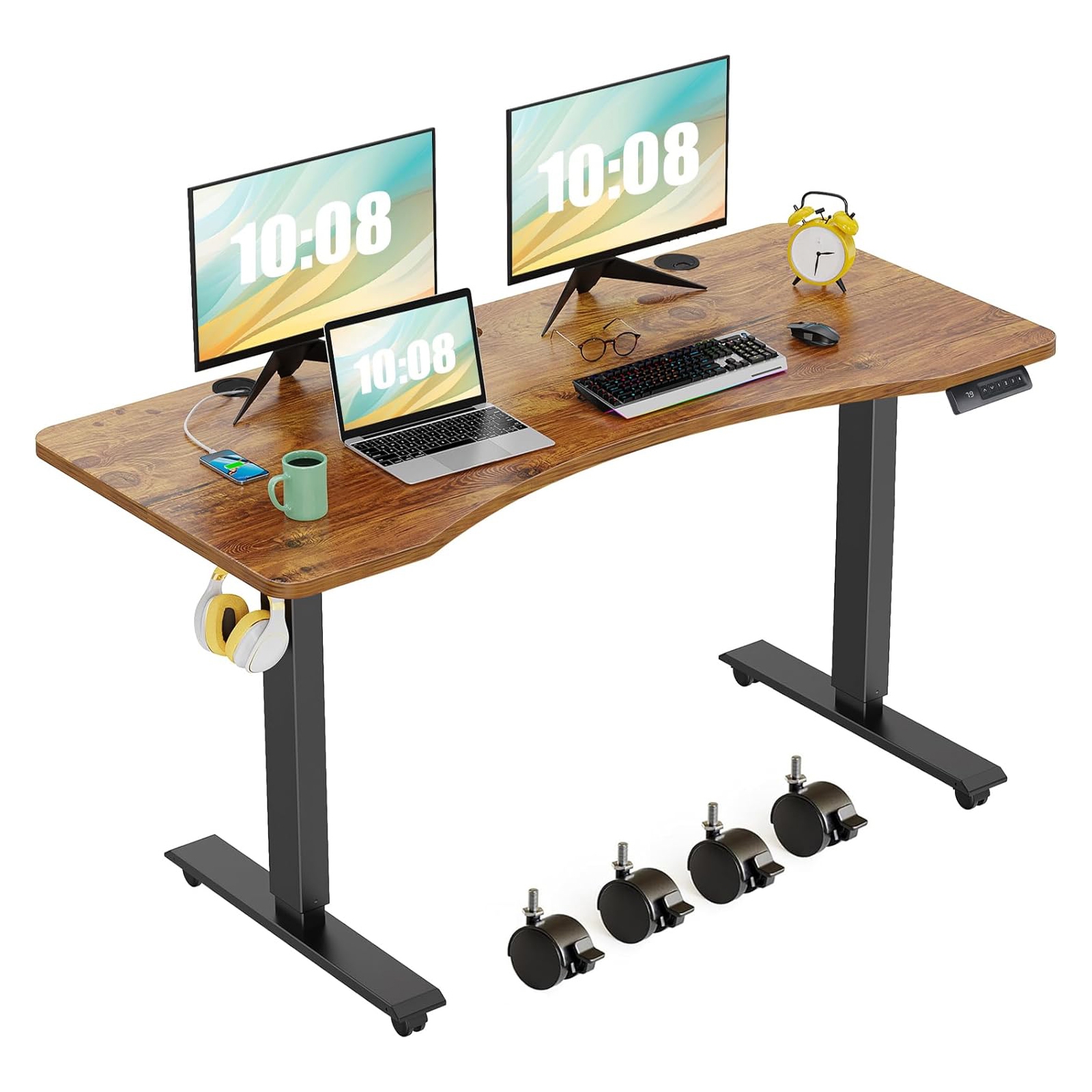 An electric standing desk with a wood grain surface, featuring two monitors, a laptop, a smartphone, a mug, and a keyboard. It includes a yellow clock, headphones on a hook, and comes with four caster wheels for mobility.