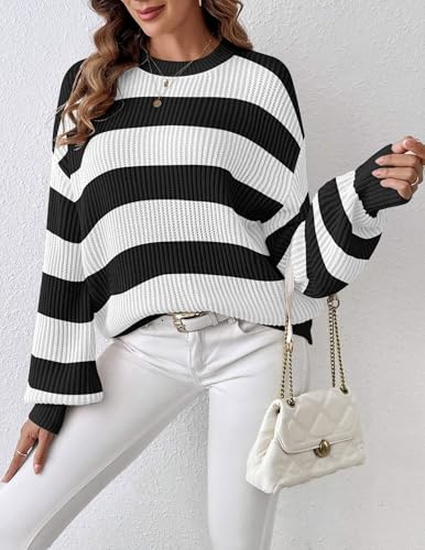 A woman is wearing a black and white striped sweater with a round neckline and long sleeves, paired with a white belt and white pants.