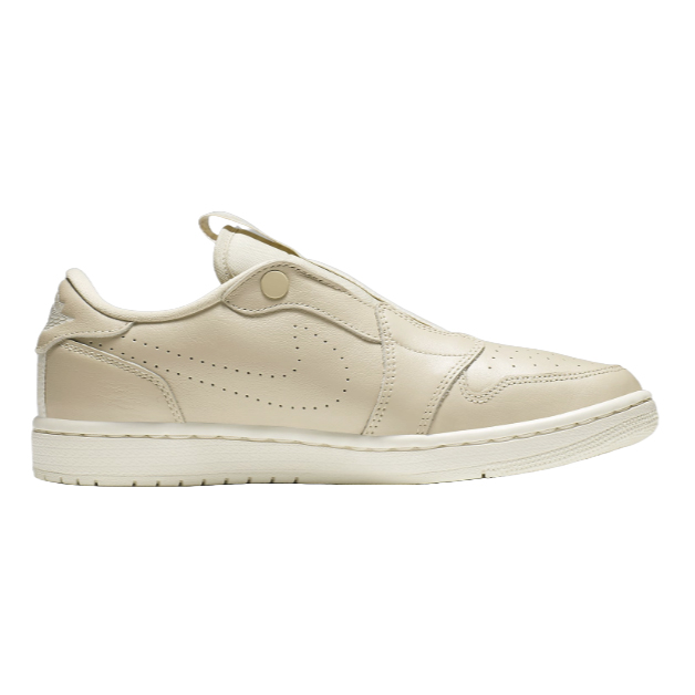A side view of a beige sneaker with a Velcro strap and perforation details.