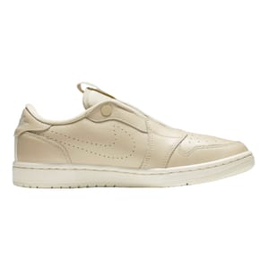 A side view of a beige sneaker with a Velcro strap and perforation details.