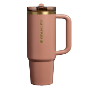 A tall, rose-colored Stanley travel mug with a handle and a translucent lid.