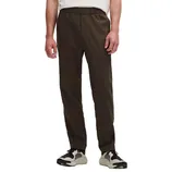 A person wearing dark brown pants with an elastic waistband, paired with white and black sneakers, and a white shirt.