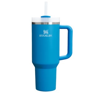 A blue Stanley travel mug with a handle and straw, featuring a stainless steel rim.