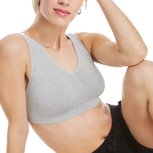 A person is wearing a light gray sports bra and black pants, sitting with one arm resting on their knee.