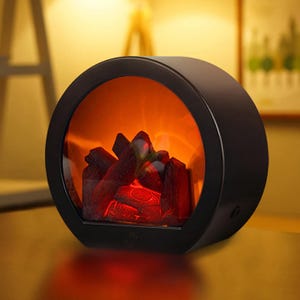 A small electric heater designed to look like a mini fireplace with glowing faux logs, providing a cozy ambiance.