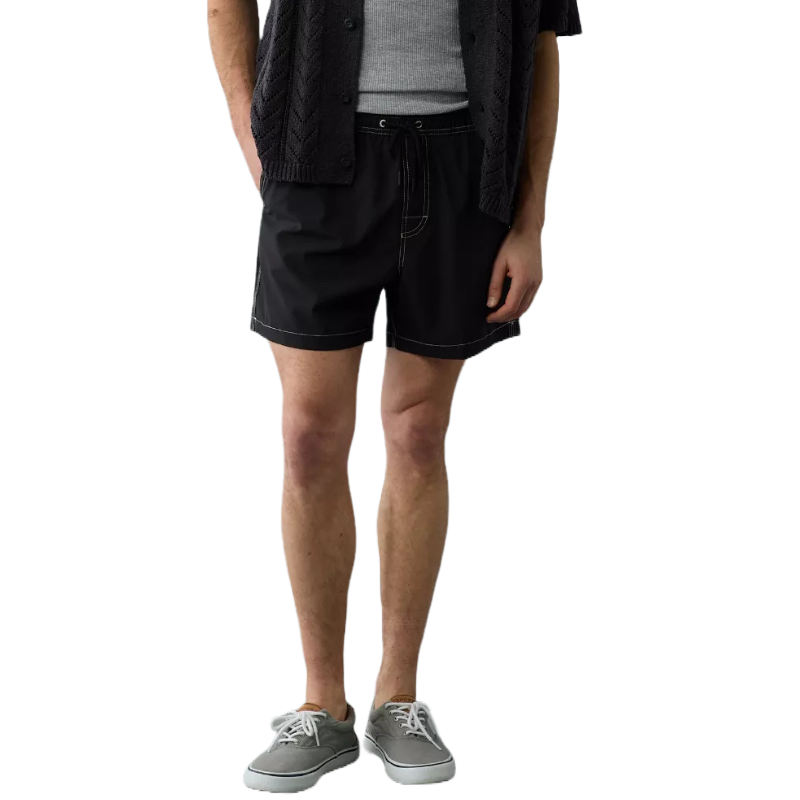 AE Men's 5\“ Flex Swim Trunk is black with contrast stitching, featuring an adjustable drawstring waist. Paired with a textured dark shirt, gray tank top, and gray sneakers.