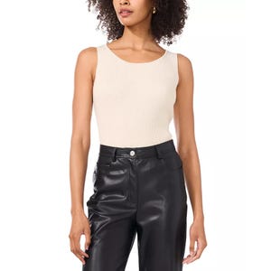 Sleeveless metallic sweater by Vince Camuto, featuring a ribbed texture and a light, neutral tone. It is paired with high-waisted black leather pants.