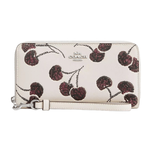 A wristlet featuring a light background with a pattern of dark red cherries and a Coach logo in the center.