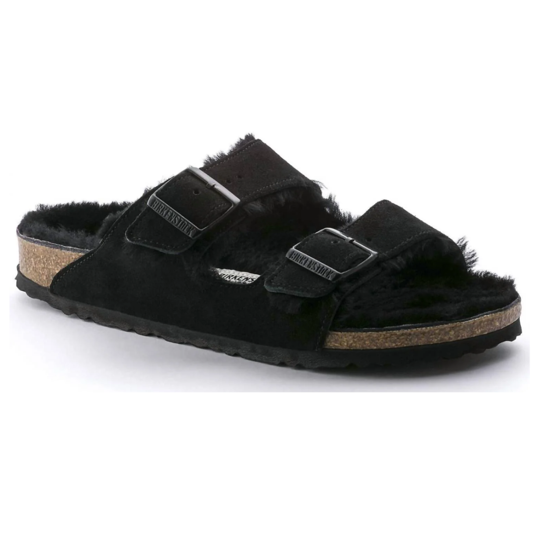 A black suede sandal with a cork sole and two adjustable straps, featuring a fuzzy interior lining.