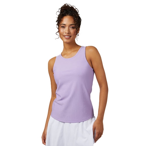 A woman is wearing a sleeveless lavender tank top with white pants, standing and smiling against a white background.