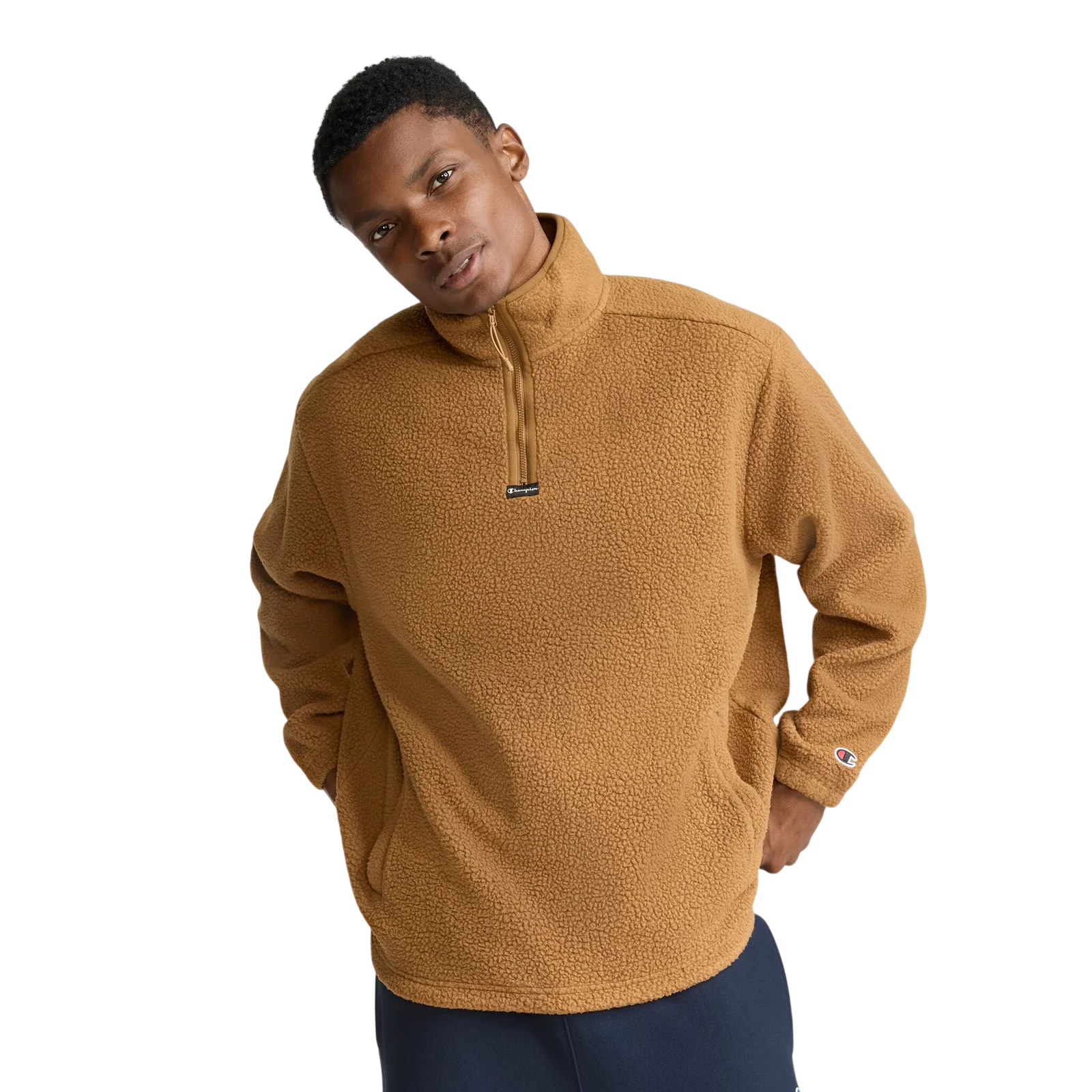 A person wears a brown fleece pullover with a quarter-zip collar and a small logo on the sleeve.