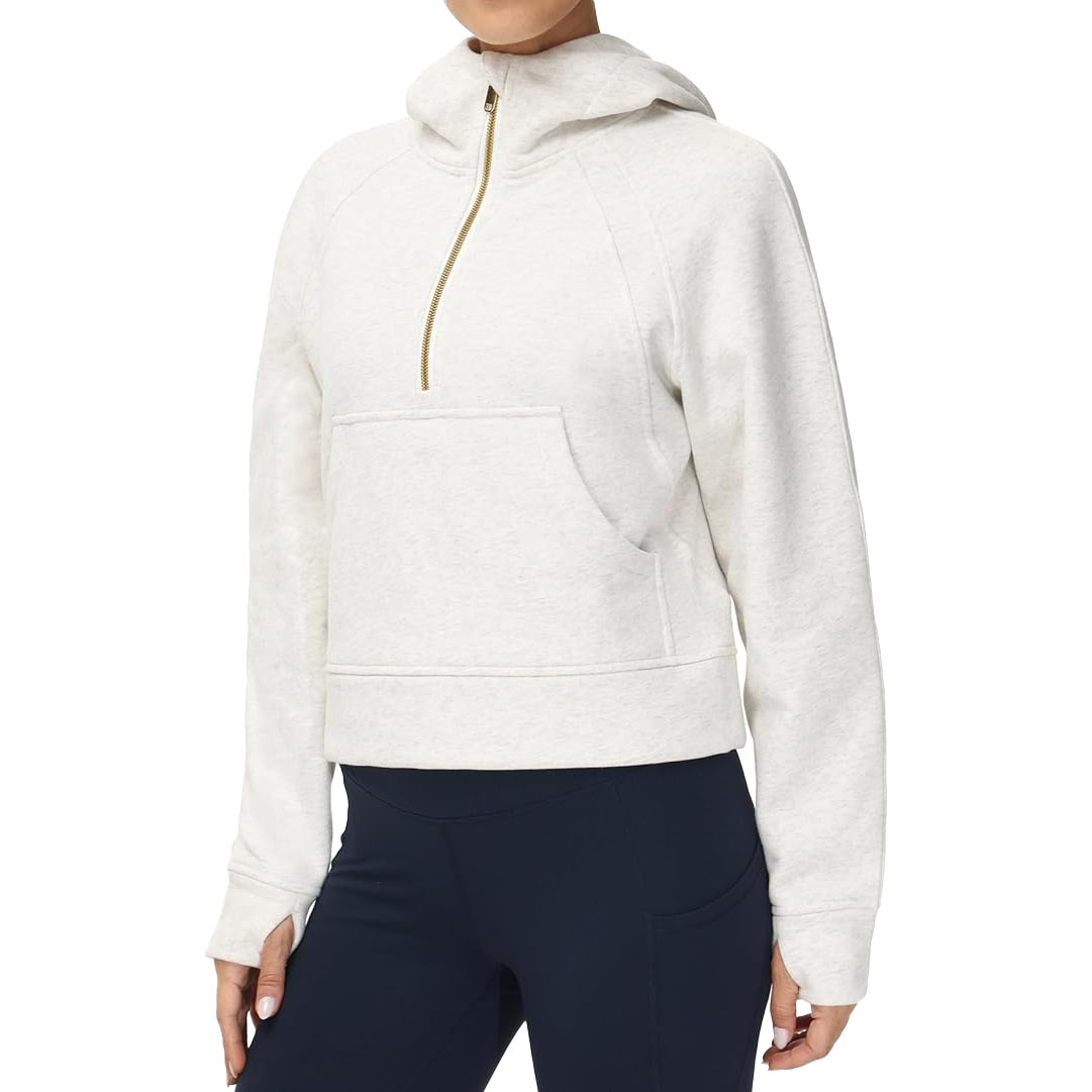 Off-white hooded pullover with a gold half-zip, kangaroo pocket, and long sleeves, paired with navy leggings.