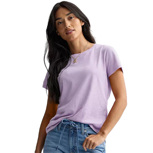 A woman wearing a light purple t-shirt and blue jeans, standing with a casual pose.