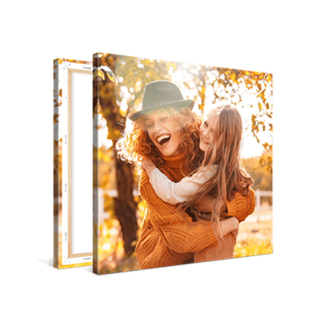 A canvas print featuring a joyful scene of a woman in a hat and a young girl embracing, surrounded by autumn foliage.