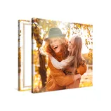 A canvas print featuring a joyful scene of a woman in a hat and a young girl embracing, surrounded by autumn foliage.
