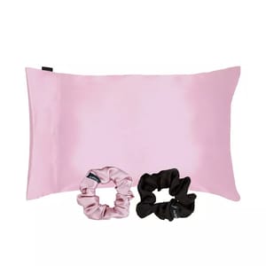 A pink satin pillowcase accompanied by two scrunchies, one in a matching pink shade and the other in black.