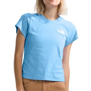 A woman is wearing a light blue t-shirt with short sleeves and a small logo on the chest. She pairs it with brown pants.