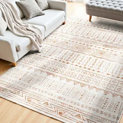 A living room features a light-colored geometric patterned area rug, a white sofa with gray cushions and a soft blanket, and a tufted gray ottoman on a wooden floor.