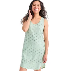 A woman is wearing a light green sleeveless dress with a subtle floral pattern. She is smiling, and the dress features a simple, relaxed fit.