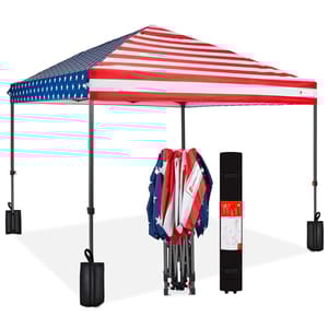 Folding canopy tent with an American flag design, shown fully set up with weights on each leg, and folded next to its carrying case.