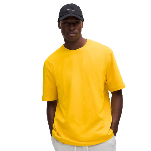 A person wearing a yellow T-shirt and a black cap.