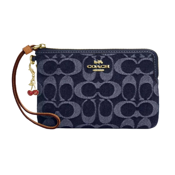 Coach Outlet wristlet in navy with a signature \“C\“ pattern, featuring a gold-tone logo and a brown leather strap adorned with a cherry charm.