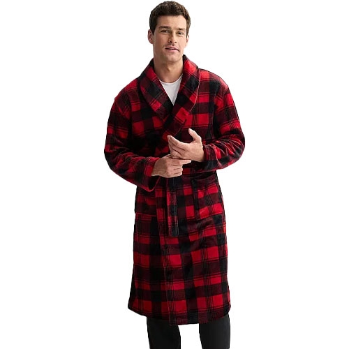 A man is wearing a red and black plaid robe with a shawl collar and belt. The robe is knee-length and paired with black pants.