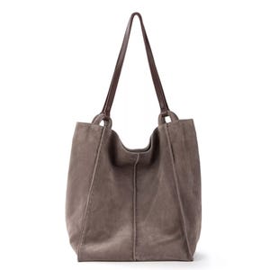 Taupe suede tote bag with dual brown leather handles and visible stitching.
