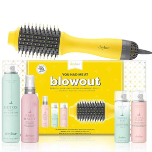 A yellow hairdryer with a brush attachment is showcased alongside four hair care products, including a dry shampoo, heat protectant, volumizing mousse, and setting spray, all part of a Drybar blowout kit.