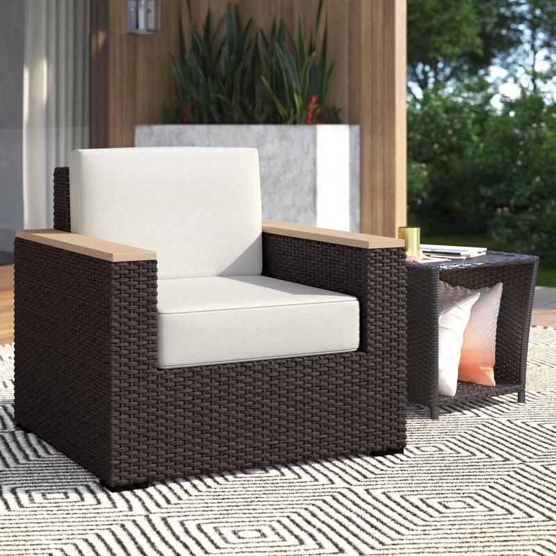 Woven outdoor armchair with light cushions and wooden armrests, accompanied by a small matching side table.
