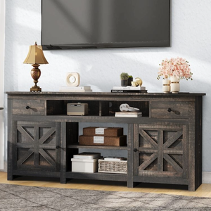 Rustic TV stand with a dark wood finish featuring two drawers, two closed cabinets with X-patterned doors, and open shelving. Decor includes a table lamp, books, a small plant, and decorative boxes.