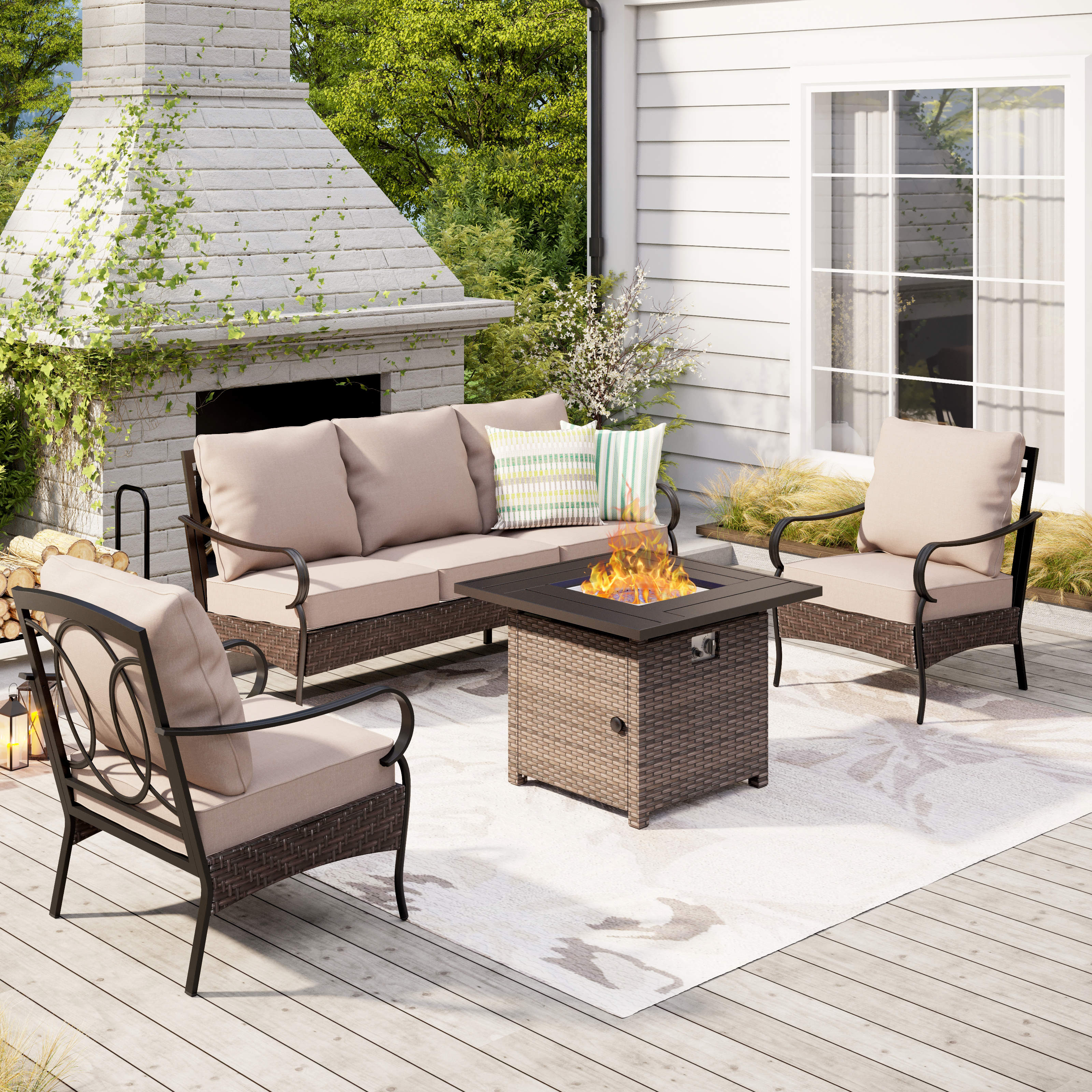 A 4-piece patio set featuring a cushioned sofa, two armchairs, and a fire pit table with a wicker base. The set is arranged on a deck with an outdoor fireplace and includes neutral-toned cushions.
