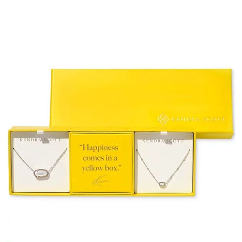 A Kendra Scott gift set featuring two necklaces inside a bright yellow box, with a card stating \“Happiness comes in a yellow box.\“