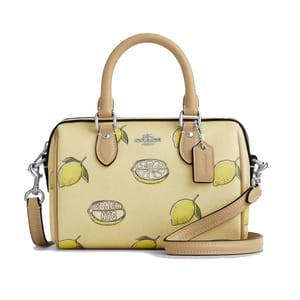 Coach handbag featuring a lemon print design, with beige handles and detachable strap.