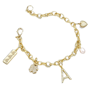 A gold-tone charm bracelet features various charms, including a rectangular tag, a clover, a letter \“A,\“ a heart, and a pearl. The chain is composed of simple interlocking links.