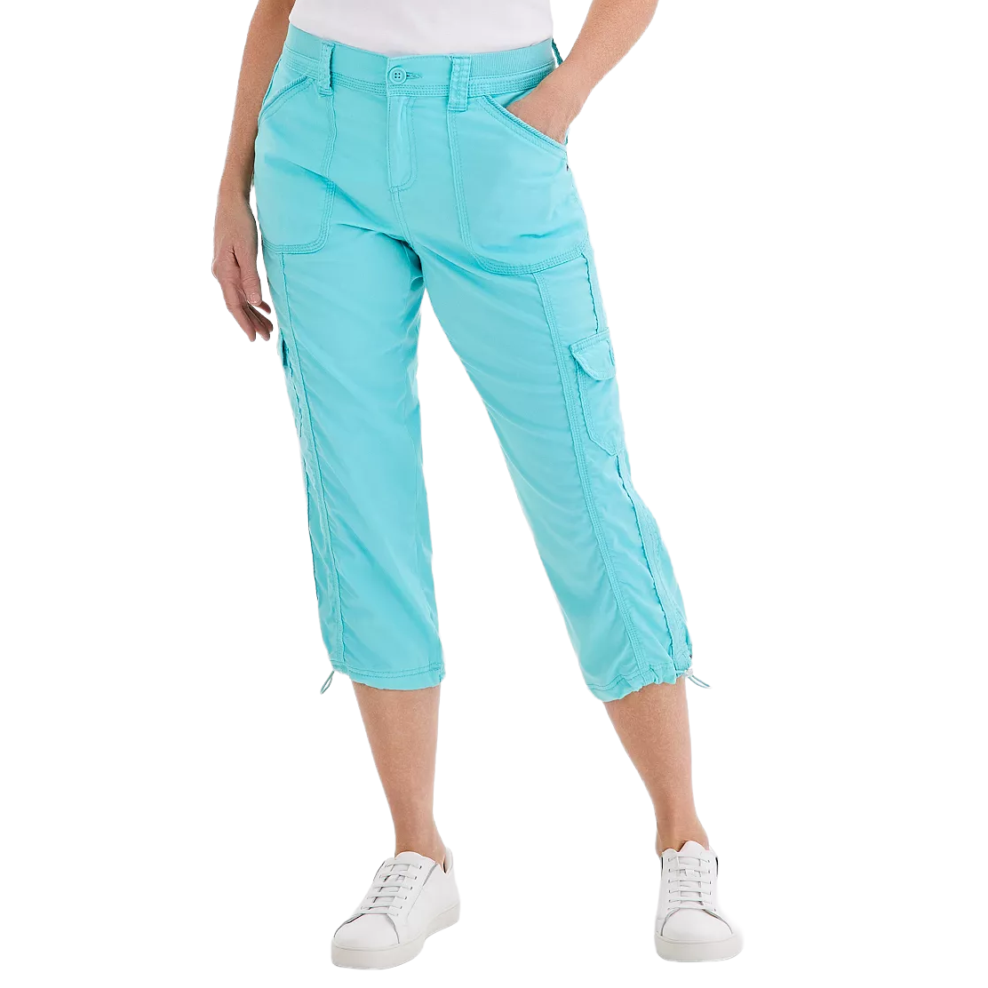 A woman is wearing light turquoise capri pants with multiple pockets and drawstring hems, paired with white sneakers and a white top.