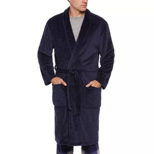 A man is wearing a navy blue bathrobe with a shawl collar and waist tie.