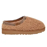 Tan slip-on slipper with a textured, fluffy exterior, branded with \“UGG\“ on the side, featuring a sturdy sole and decorative stitching around the opening.