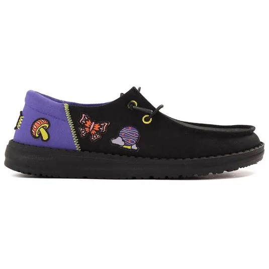 A black slip-on shoe featuring colorful patches, including a mushroom, butterfly, and a space-themed design, with a purple heel accent and black sole.