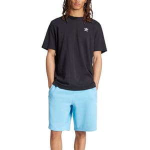 A person is wearing a black T-shirt with a small emblem on the chest and light blue shorts.